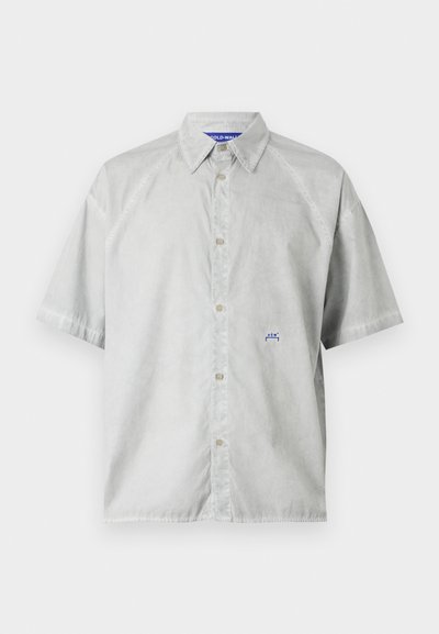 Korte mouwen, lichtgrijze knoopshirt van gladde stof. Heeft een puntige kraag en een klein blauw logo op de borst.