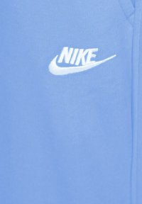 Prenda Nike de color azul claro con un logo blanco bordado. La tela parece suave con una textura blanda y mínimos detalles de costura.
