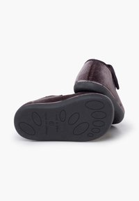Pantofole di velluto marrone con suole in gomma nera. Forma arrotondata, design senza chiusure, caratterizzate da una texture morbida e dettagli di cucitura discreti.