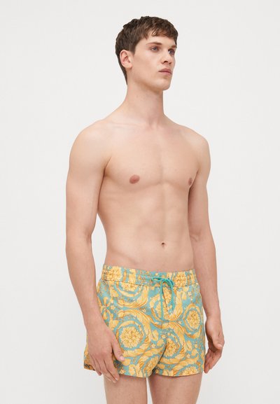 Shorts de bain avec un motif floral en jaune et turquoise, taille élastique avec cordon de serrage, longueur courte, tissu léger.