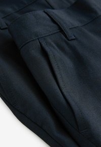 Pantaloni blu navy realizzati in tessuto testurizzato, con frontale piatto, tasche laterali e una vita sagomata.