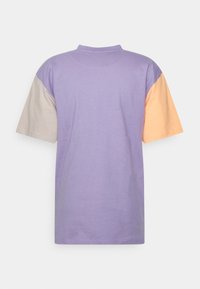 Triko s krátkým rukávem v levandulovém provedení, s béžovými a oranžovými akcenty na rukávech, vyrobené z měkké bavlny.