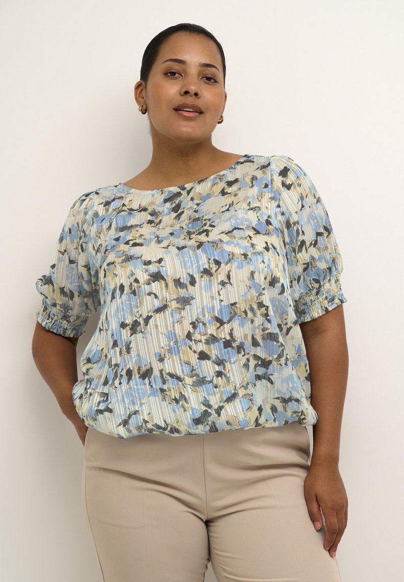 Blusa leggera plissettata in un motivo astratto blu, crema e nero. Presenta maniche corte elasticizzate e un collo rotondo.