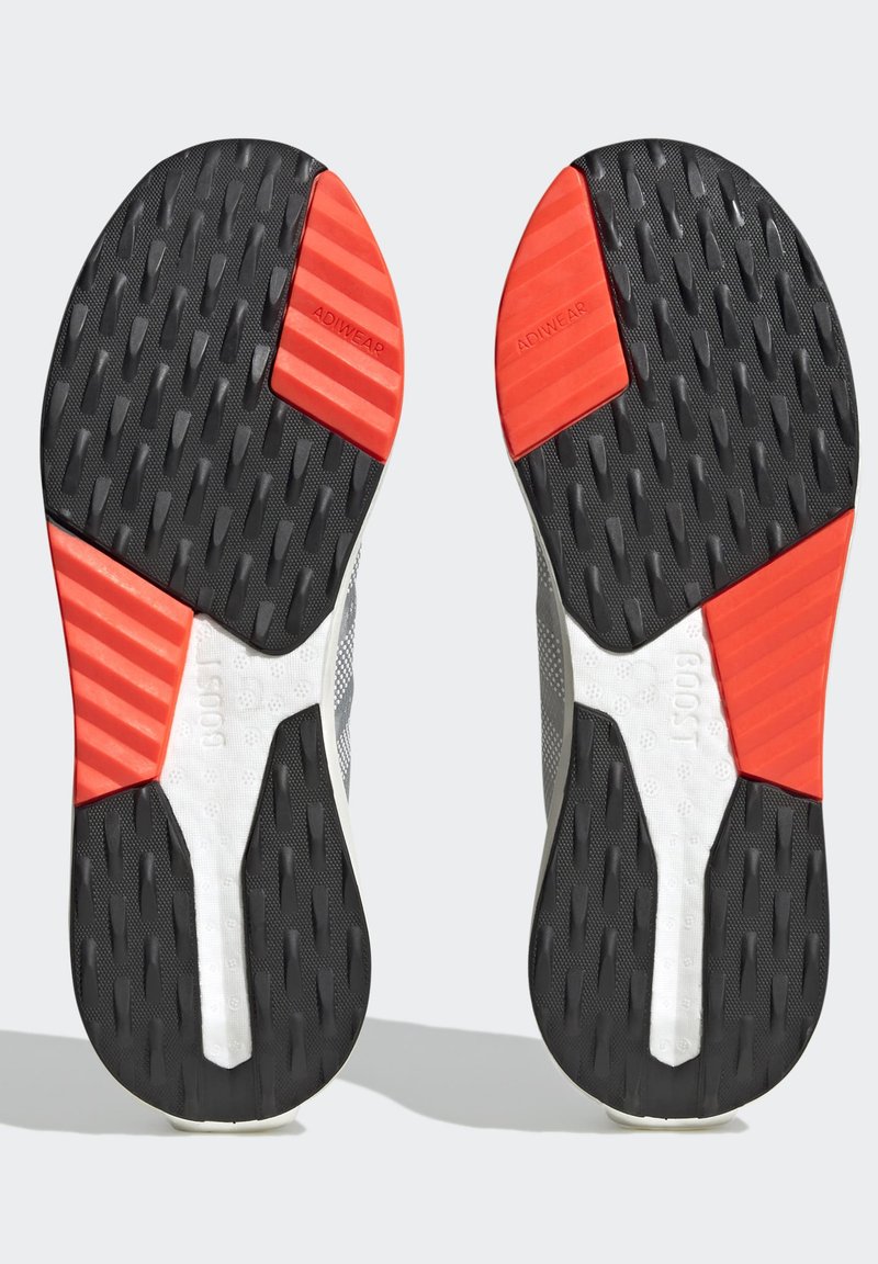Sportschuhsohlen mit einem schwarzen Profilmuster, roten und grauen Akzenten. Enthält strukturierte Abschnitte und Markenelemente in einem leichten Design.