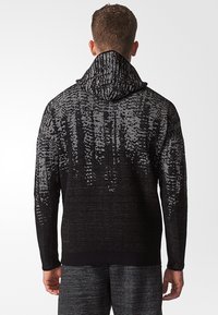 Black and gray patterned knit hoodie with a textured design, featuring a tall, split neckline and soft fabric. The hem is ribbed.