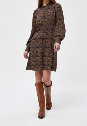 Robe à manches longues en navy avec un motif floral orange, devant à boutons et un col. Associée à des bottes en cuir marron montantes jusqu'au genou.