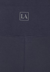 Morske ženske legice z raztegljivim pasom. Vrh pasu je okrašen s subtilnim logotipom "LA" natisnjenim znotraj kvadrata. Gladka, teksturirana tkanina.