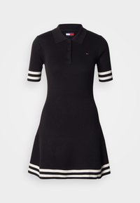 Melna ribaina polo stilā kleita ar īsām piedurknēm, baltas svītras uz aprocēm un apakšmalas, ar pogu aizdari pie kakla.