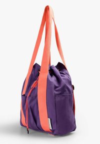 Sac fourre-tout en tissu violet avec de larges anses corail et une fermeture à cordon, doté de poches extérieures sur fond blanc uni.