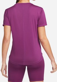 Lila atletisk topp med korta ärmar i mjukt material, med rundad halsringning och diskreta sömdekorationer, matchad med tillhörande shorts.