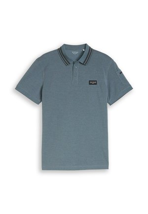 Niebieska koszulka polo z krótkim rękawem, dwuguzikowym dekoltem, paskowanym kołnierzykiem oraz małą czarną naszywką z logo na lewej piersi i detalem na kieszeni z przodu na rękawie.