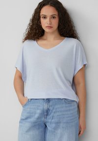 Maglietta a V blu chiaro con maniche corte, caratterizzata da una vestibilità relaxed e una texture morbida, abbinata a jeans in denim chiaro a vita alta.