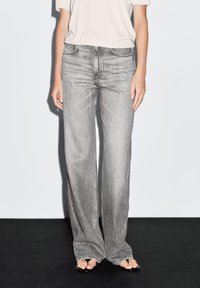 Gray wide-leg jeans made of denim with a faded wash, featuring five pockets, belt loops, and subtle stitching details.