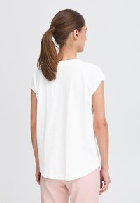 Vit kortärmad t-shirt med rundad fåll, tillverkad av mjukt tyg, med avslappnad passform och minimalistisk design. Baksidan betonar enkelhet.