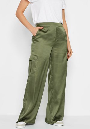 Olijfgroene satijnen cargo-broek met brede pijpen, zijzakken en een gladde textuur, gecombineerd met een witte t-shirt en casual schoenen.