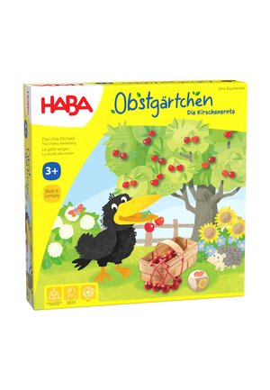 Spieleschachtel für Kinder mit einer Zeichentrickzeichnung eines schwarzen Vogels, der Kirschen von einem Baum in einen Korb pflückt, umgeben von Sonnenblumen und einem Igel.