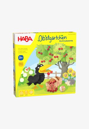 Spieleschachtel für Kinder mit einer Zeichentrickzeichnung eines schwarzen Vogels, der Kirschen von einem Baum in einen Korb pflückt, umgeben von Sonnenblumen und einem Igel.