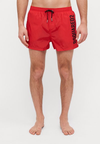Shorts de bain rouges en matériau léger, avec un logo noir sur le côté, une taille élastique avec cordon de serrage et une finition lisse.