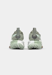 Groene sportschoenen met een gestructureerde bovenkant, reflecterende accenten en een witte tussenzool. Voorzien van een trekband en een patroon van rubberen loopzool.