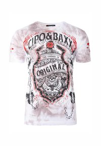 T-shirt bianco in cotone con stampa grafica nera e rossa. Il design include un emblema con testo, catene decorative e dettagli astratti di spruzzi.