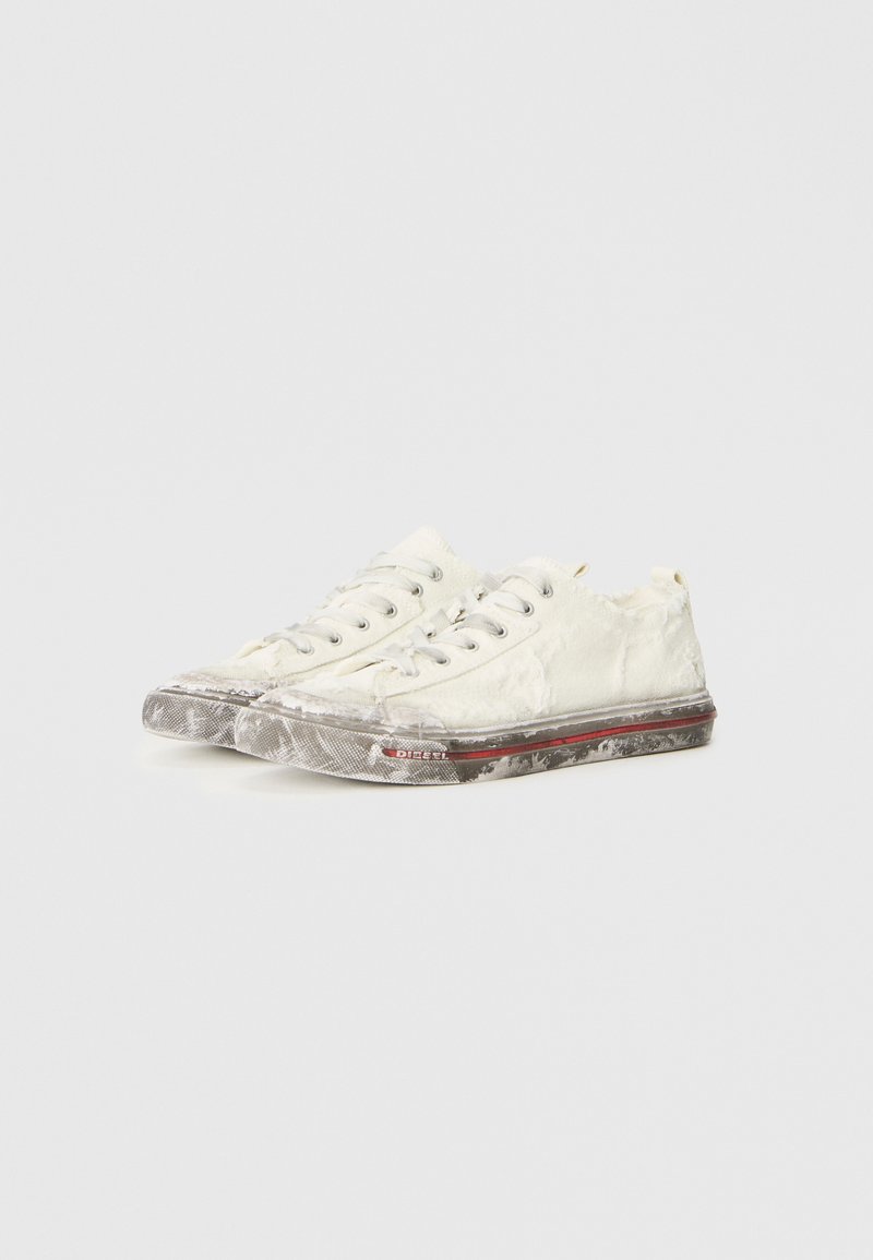 Zapatillas de lona blancas con bordes deshilachados, parte superior texturizada, suelas de goma grises y acentos rojos a lo largo del lateral. Diseño con cordones, con un branding mínimo.