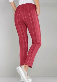 Rood gestreepte broek met een slim fit en een elastische tailleband, gemaakt van soepel stof. Gecombineerd met witte instappers met metallic accenten.