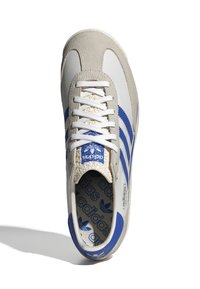 Vita och grå sneakers med blå ränder, i mocka och syntetiska material, rund tå, vita snören samt en märkesinspirerad blå innersula och tunga.