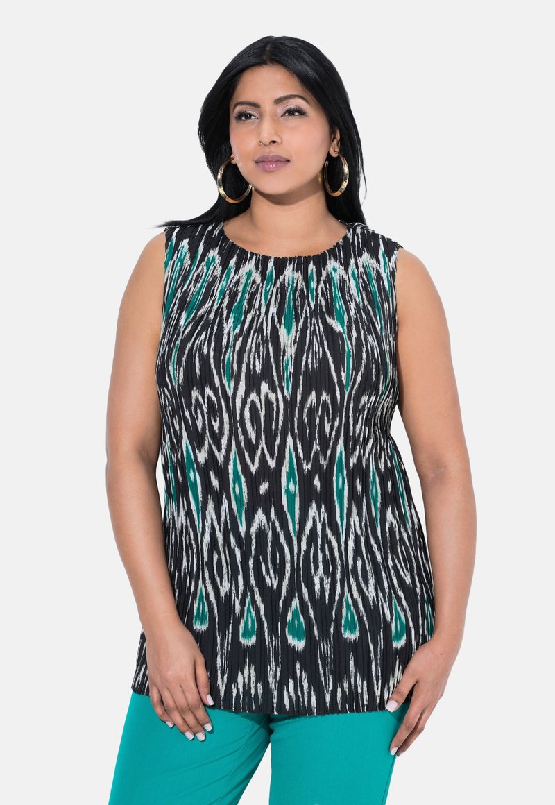 Top sin mangas con un patrón ikat en blanco y negro y acentos en verde azulado. Presenta un escote redondo y un corte holgado, combinado con pantalones en verde azulado.