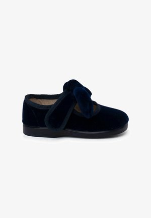 Marineblaue Samt-Schuh mit abgerundetem Zehenbereich, ausgestattet mit einer großen, plüschigen Schleifenverzierung und elastischem Besatz am Ausschnitt, ergänzt durch eine schwarze Sohle.