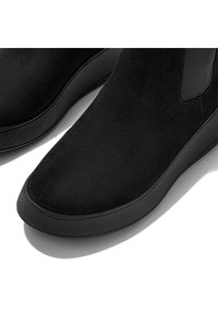 Botas de tobillo de ante negro con textura suave, puntera redonda, paneles laterales elásticos y suela de goma para agarre.