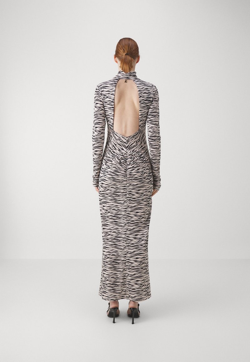 Sukienka z długim rękawem o wzorze czarno-beżowych pasi zebry, z odkrytymi plecami, dopasowaną sylwetką i długością do ziemi.