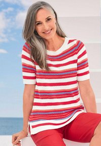 Gebreide trui met korte mouwen in rood, wit en blauwe strepen, met een ronde hals. Gecombineerd met rode shorts, voorzien van zijslits voor extra comfort.