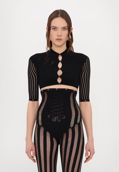 Haut noir court à manches courtes avec des ouvertures en forme de clé. Leggings noirs taille haute avec un motif rayé et des détails à lacets.