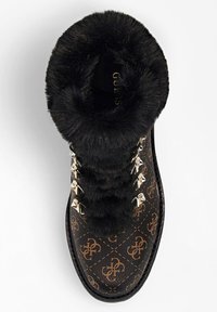 Bottes noires en fausse fourrure avec un extérieur à motif marron, dotées d'œillets et de lacets en métal doré, et d'un design à bout rond.