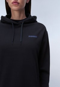 Sudadera negra de tejido suave, con un bolsillo frontal, capucha con cordones y un pequeño logo azul en el pecho izquierdo.