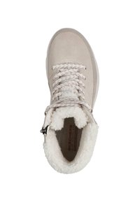 Botín beige de ante con un forro blanco y esponjoso, puntera redonda, tacón reforzado y cordones gruesos. Cuenta con una cremallera lateral para un acceso fácil.