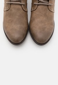 Chaussures en cuir marron avec une finition lisse, bout pointu et accents de couture contrastés. Présentent des lacets marron et une semelle noire robuste.