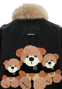 Chaqueta de denim negra con tres apliques de osito de peluche en tonos crema y marrón claro, con acentos de ropa negra y un cuello de piel sintética. Etiqueta de MWM Design incluida.