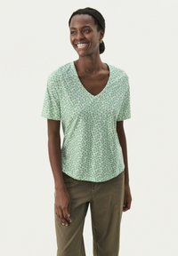 Grön kortärmad V-ringad t-shirt med ett blommönster i mörkgrön och vitt, tillverkad av mjukt tyg, med en avslappnad passform och rundad nederkant.