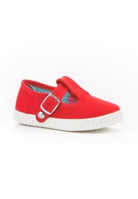 Zapato de lona rojo con suela de goma blanca, que cuenta con una correa con hebilla de plata y un forro interior con un diseño estampado. Diseño de punta redonda.