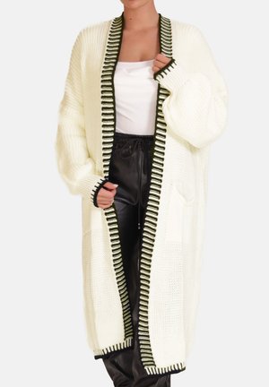 Strikket cardigan i hvid med grønstribet kant, åben front og sidelommer, med løse ærmer og et tekstureret mønster.