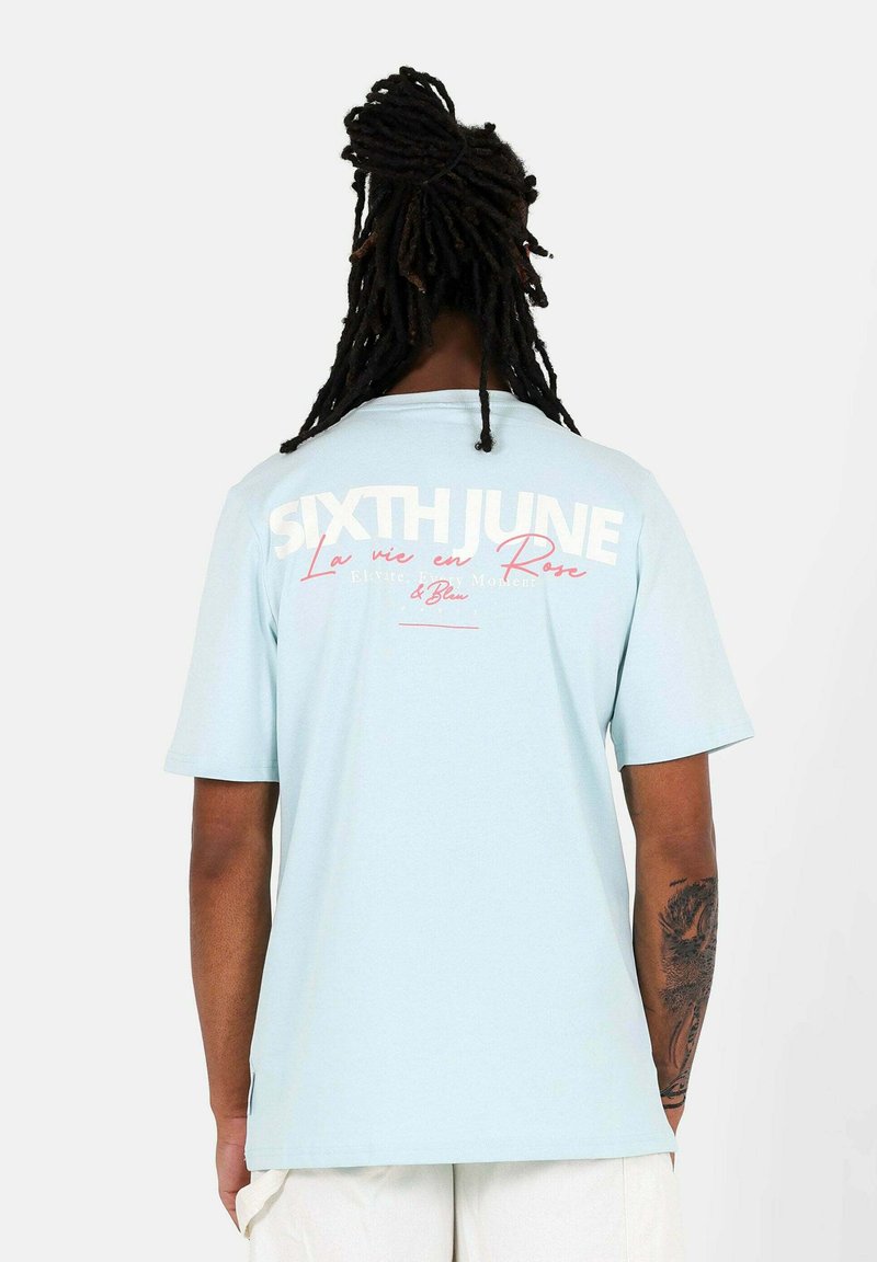 Ljusblå t-shirt med kort ärm och vit samt rosa text på ryggen, med grafik av "SIXTH JUNE" och "La vie en Rose".