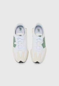 Baskets de sport blanches et vertes avec une tige texturée, dotées de lacets blancs, d'une forme distinctive et d'une semelle noire accentuée.