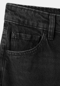 Close-up of black denim jeans showing front pocket, belt loop, and visible diagonal fabric texture.