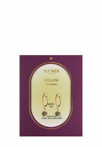 Goldfarbene Creolen mit runden Zirkonia-Akzenten. Präsentiert auf einer weißen und lila Karte, beschriftet mit "Gelber November."