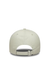 Beige baseball cap with a curved visor, adjustable strap at the back, two eyelet holes on each side, and a textured fabric finish.