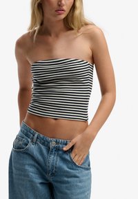 Haut bustier ajusté à rayures bleu marine et blanc, fabriqué en tissu doux. Associé à un jean en denim bleu clair taille haute avec une coupe classique.