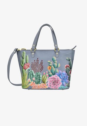 Grijze leren totebag met levendige geborduurde cactussen en vetplanten in roze, groen en blauw. Inclusief dubbele handgrepen aan de bovenkant en een verstelbare schouderriem.