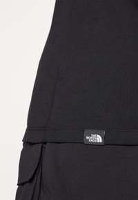 Černé tričko s kulatým výstřihem, vyrobené z měkké látky. U hému se nachází malá nášivka s logem "The North Face".