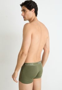 Groene katoenen boxershorts met een witte logo tailleband. De stof lijkt zacht met een nauwsluitende pasvorm, wat zorgt voor een gladde textuur en het ontbreken van patronen.